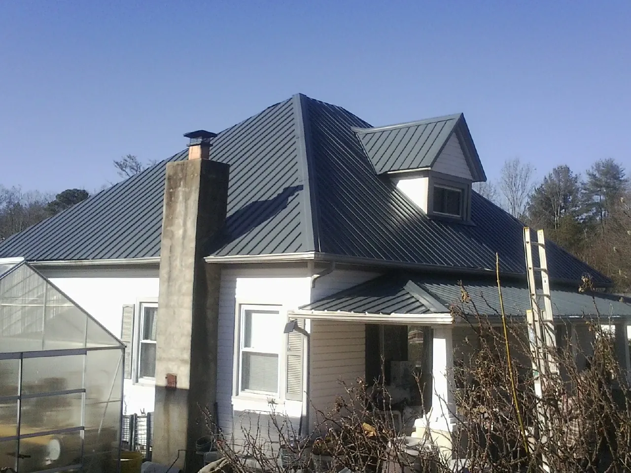 Dark blue standing seam metal roof on a white farmhouse with dormer — Slate & Tile Roof Repair by Roofing Brothers in Kenoza Lake