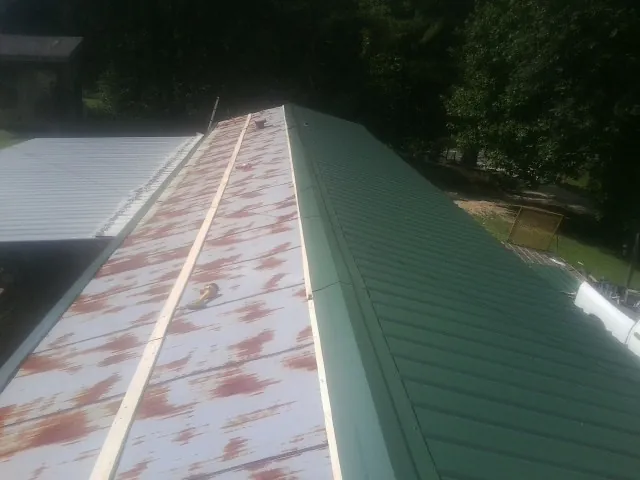 Old rusted panels beside newly installed green metal roofing — Wind Damage Roof Repair by Roofing Brothers in Kenoza Lake