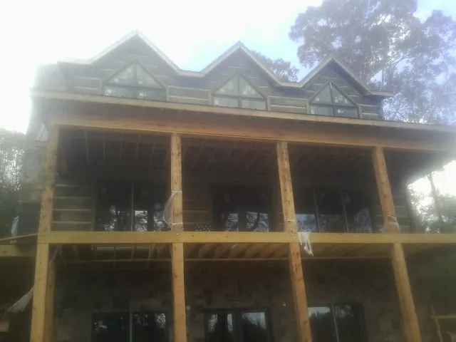 Dormers and porch framing on a large log home under construction — Roof Coating work by our crew in Kenoza Lake