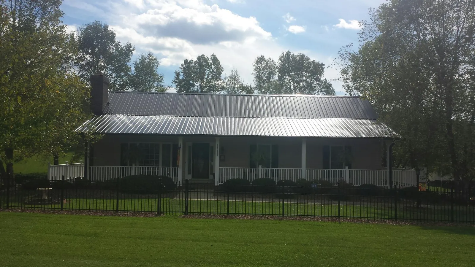 Gray metal roof on a brick ranch with a full width front porch — Gutter Guard Installation work by our crew in Kenoza Lake