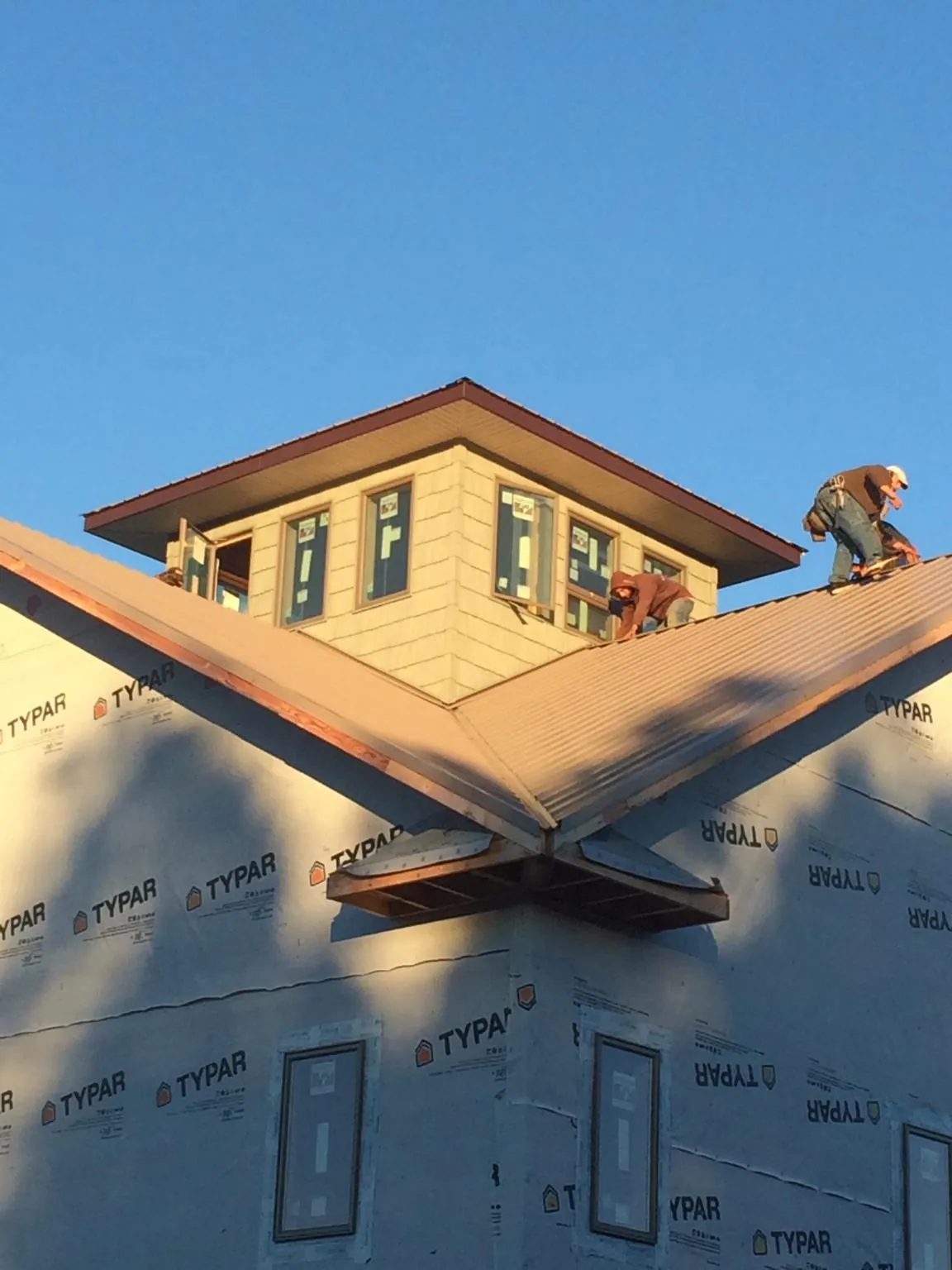 Roofers working around a rooftop cupola on a new metal roof at sunset — Roof Waterproofing in Kenoza Lake by Roofing Brothers